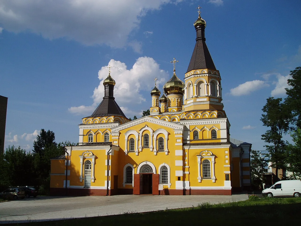 Покровська церква в Києві з жовтими стінами та темними банями.