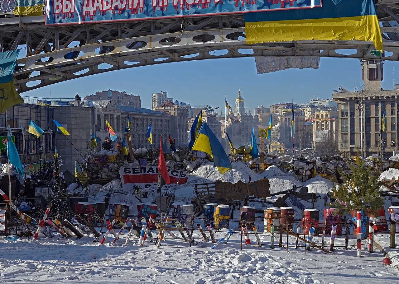 Євромайдан у Києві взимку, барикади та українські прапори.