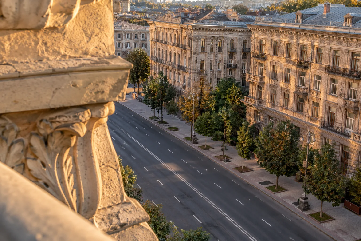 Київська вулиця з історичною забудовою, деревами й кам’яною архітектурною деталлю на передньому плані