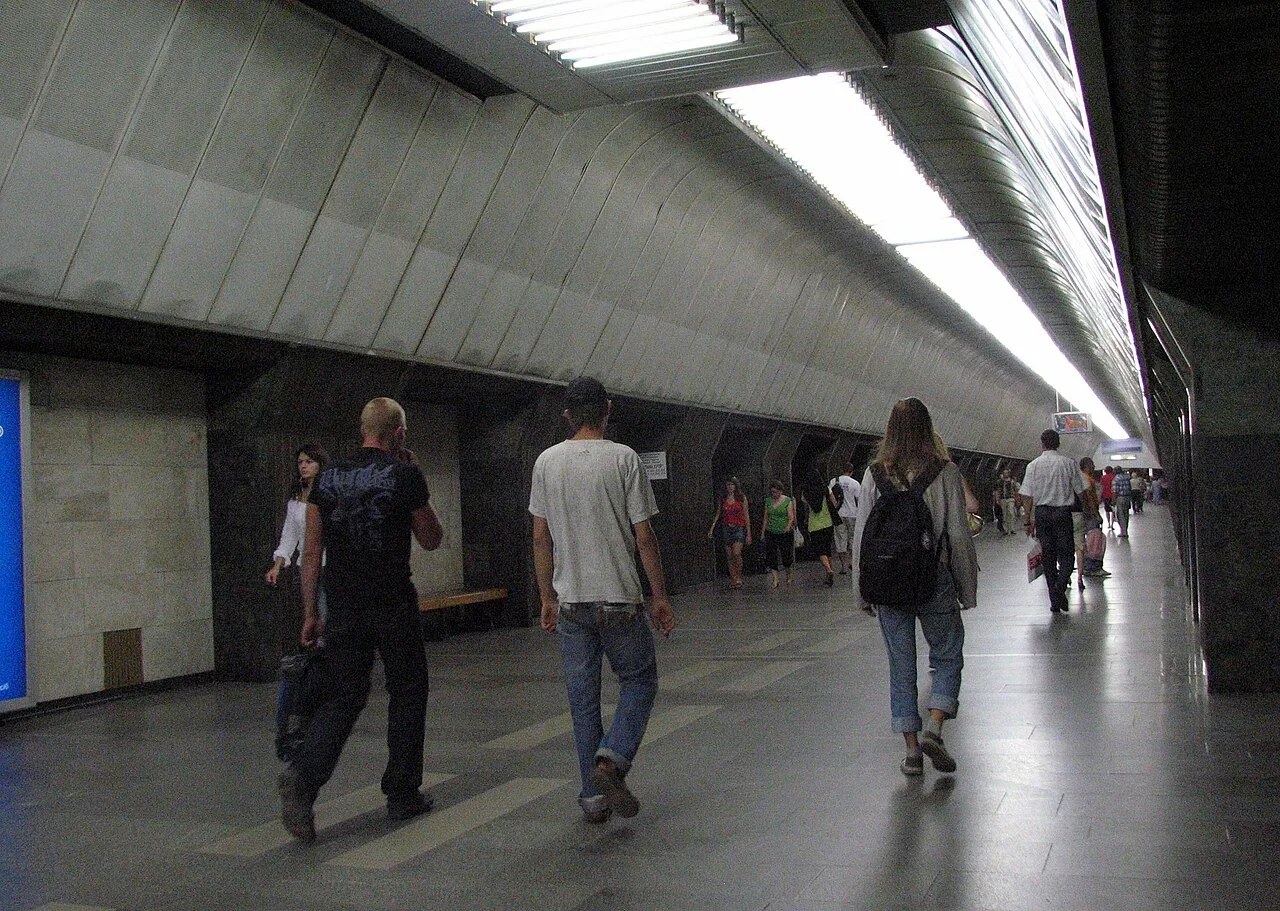 Зал станції метро «Палац спорту» з похилою металевою стелею та пасажирами Зал станції метро «Палац спорту» з похилою металевою стелею та пасажирами