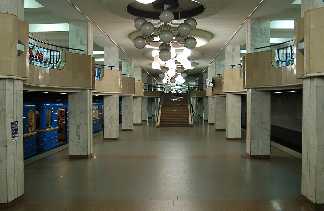 Зал станції метро «Академмістечко» зі сходами та поїздом Зал станції метро «Академмістечко» зі сходами та поїздом